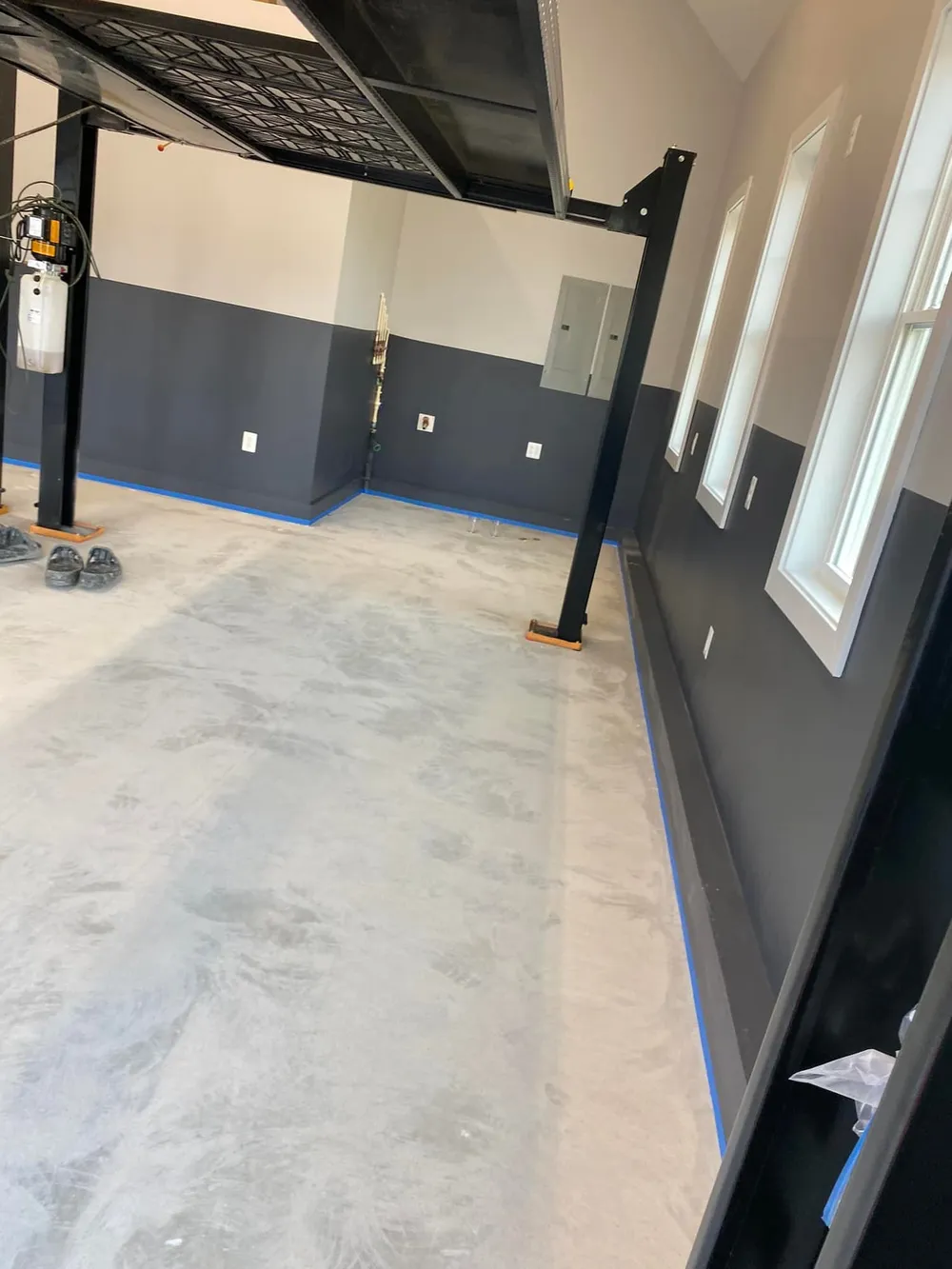 Bare concrete garage floor with edges masked during a UGF project